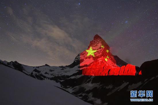 4月19日,瑞士采尔马特市旅游局用灯光将一面五星红旗投射到附近阿尔卑斯山脉的马特洪峰。 新华社发(瑞士采尔马特市旅游局供图)