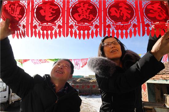  在河北省张北县德胜村，徐海成（左）和妻子裴秀平在家中布置春节装饰（2018年2月9日摄）。新华社记者 牟宇 摄