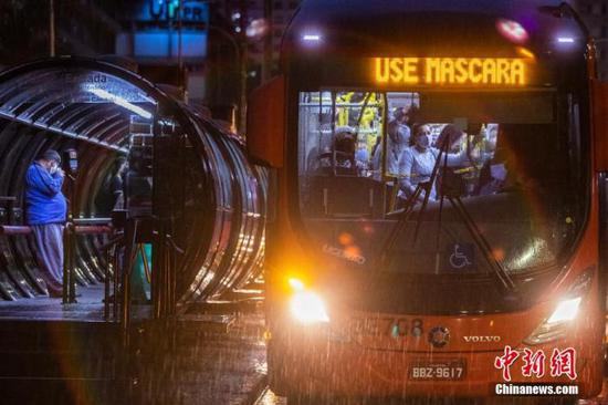 图为巴西公共交通上的民众戴着口罩乘车。
