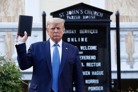  特朗普手举圣经在教堂门前拍照。在其前往教堂前，警察向白宫外聚集的抗议者释放催泪瓦斯、发射橡皮子弹，以驱散人群为特朗普开出一条道路。（美联社）
