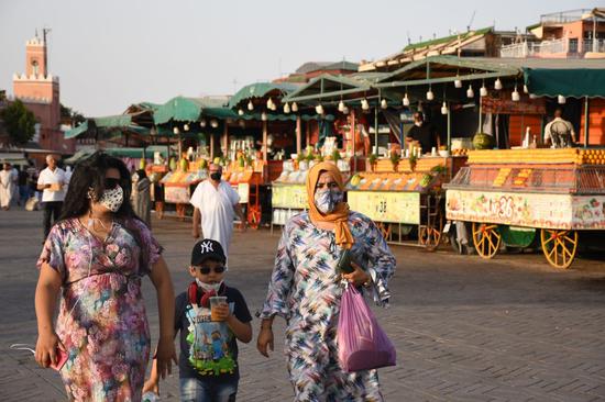 7月22日，人们戴着口罩在摩洛哥马拉喀什的杰马夫纳广场上行走。（新华社发，查迪摄）