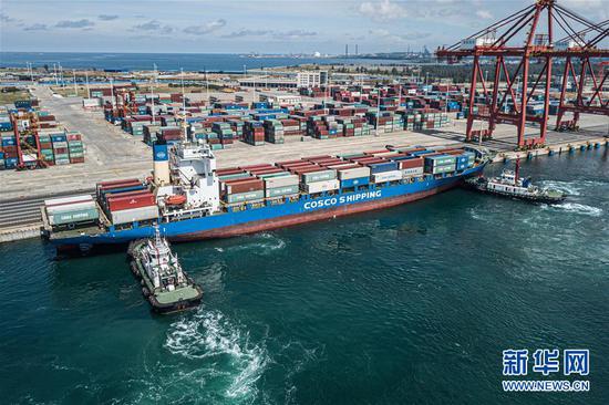 一艘中远海运集装箱货轮在两艘拖轮的辅助下，靠泊进海南洋浦小铲滩码头（9月23日摄，无人机照片）。新华社记者 蒲晓旭 摄
