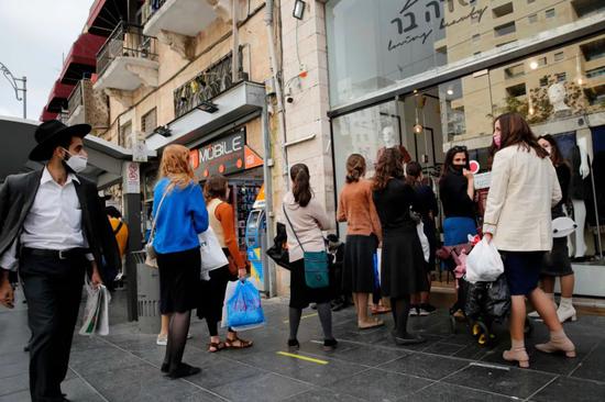 11月10日，在以色列耶路撒冷，人们排队等待进入一家街头商店。新华社发（吉尔·科恩·马根摄）