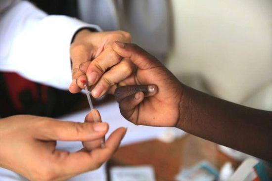 2018年12月8日拍摄的照片显示，在马拉维南部布兰太尔市卡迪迪村卫生院，第六批中国援马拉维医疗队医生在义诊活动中为当地居民检测疟疾