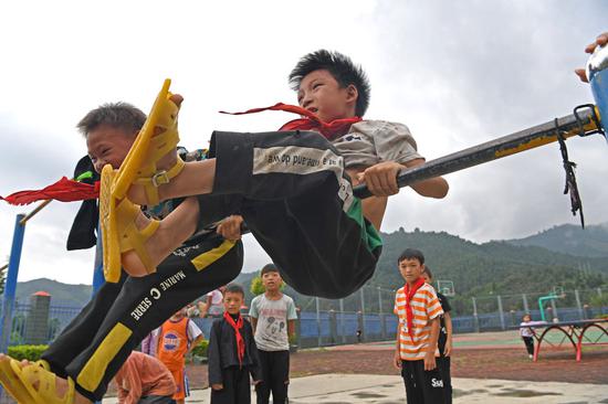 广西百色市凌云县泗城镇览金小学学生在玩单杠。新华社记者 周华 摄