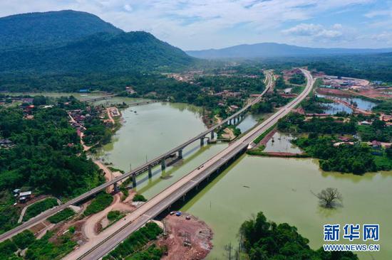 这是10月21日在老挝万象省航拍的建设中的万万高速桥梁（右）和中老铁路桥梁（左）。新华社发（云南建投集团供图）