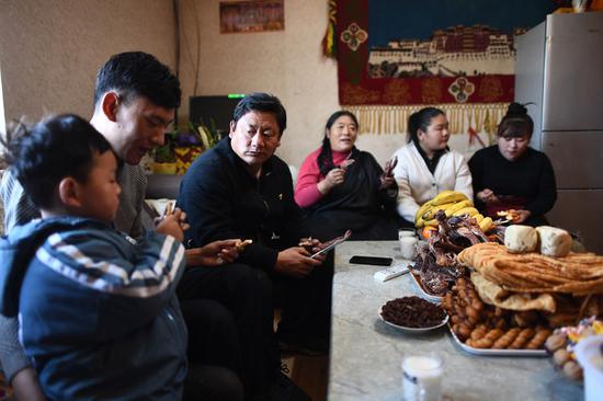 ↑ 3月10日，尕玛松保（左三）和家人在家中吃早饭。