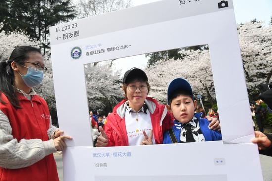 3月13日，来自沈阳经济技术开发区人民医院、去年援鄂期间在武汉雷神山医院工作的邵丹（中）带着孩子来武汉大学赏樱。