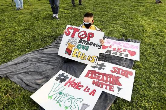 3月20日，一名男孩手持标语参加美国加利福尼亚州洛杉矶县阿尔汉布拉市举行的“停止仇恨亚裔”烛光仪式，抗议针对亚裔的暴力和仇恨犯罪。新华社发