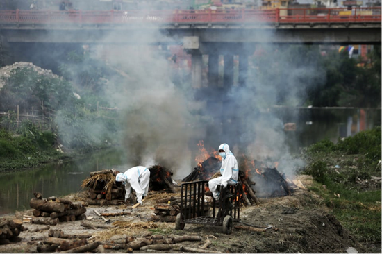 火葬现场的医护人员和升起的浓烟。来源：尼泊尔时报