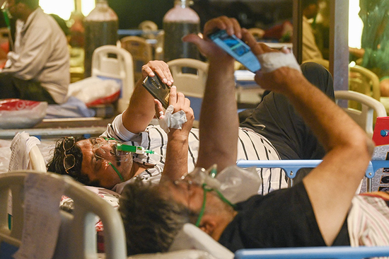 2021年5月7日，印度新德里的一家医院，新冠肺炎患者在病床上查看手机。