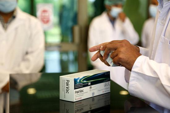 6月1日，在巴基斯坦伊斯兰堡，工作人员展示本地灌装生产的中国康希诺新冠疫苗。新华社发（艾哈迈德·卡迈勒摄）