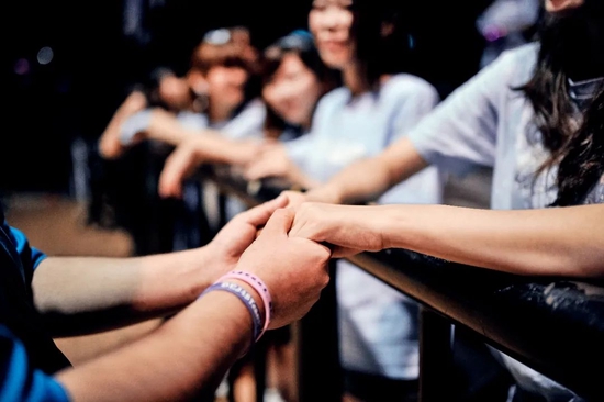 在演出后的握手会，一位粉丝紧紧握住女孩的双手。
