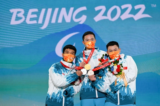 3月7日，中国选手冠军纪立家（中）、亚军王鹏耀（左）和季军朱永钢在北京2022年冬残奥会残奥单板滑雪男子障碍追逐（UL级）比赛奖牌颁发仪式上。新华社记者 胡超 摄