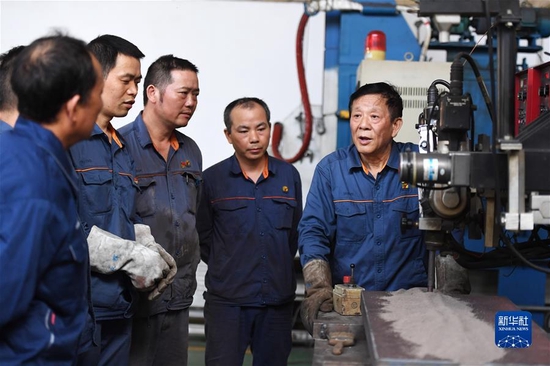 艾爱国（右一）在湖南华菱湘潭钢铁有限公司实验室和同事探讨焊接技术（2021年6月12日摄）。新华社记者 薛宇舸 摄