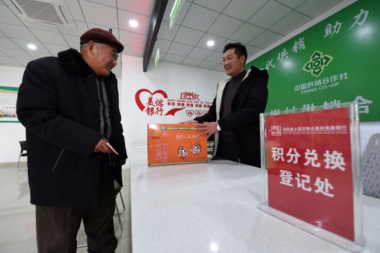 在安徽省滁州市凤阳县小岗村，村民缪守鲁（左）在村里“美德银行”用积分兑换生活物品（2021年1月30日摄）。新华社记者 周牧 摄