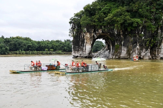 游客在广西桂林乘坐竹筏游览象鼻山（2022年6月29日摄） 曹祎铭摄/本刊