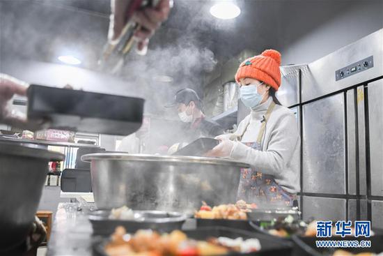 2月26日,爱心人士“雨衣妹妹”(右)在分装盒饭。 新华社记者 程敏 摄