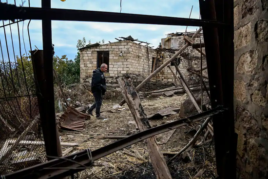  在纳卡地区首府斯捷潘纳克特，一位居民走在自己被炸毁的院子里。（图源：Getty）