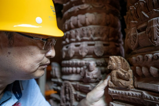 △2019年10月10日，在尼泊尔加德满都杜巴广场，中国派出的文物修复队技术主管在九层神庙修复现场查看文物。