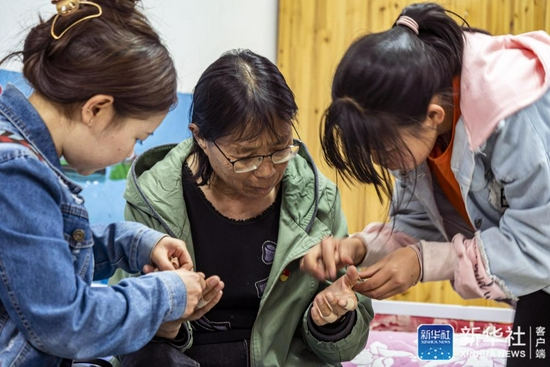  每天回到福利院，孩子们都会帮张桂梅撕掉贴了一天的止痛胶带（3月23日摄）。新华社记者 江文耀 摄