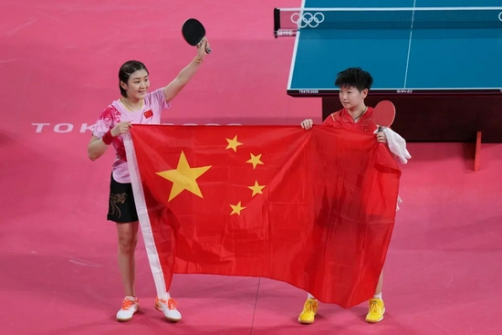 7月29日，陈梦（左）和孙颖莎在比赛后携手共展国旗。