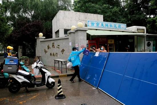 7月29日，北京新增确诊病例所在的居民小区已封闭，超市送货及外卖人员向小区内递送居民购买的生活用品。图/澎湃影像