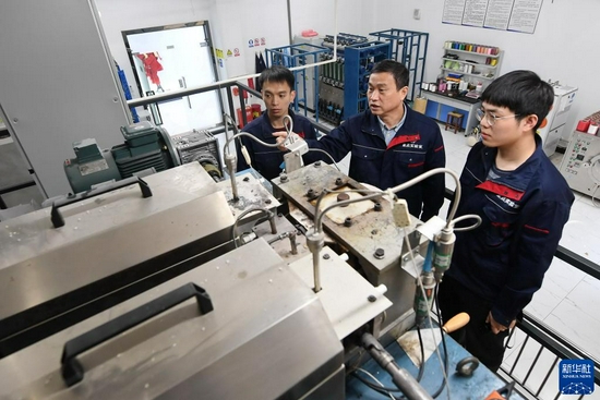 福建闽江学院服装与艺术工程学院教授李永贵(中)在“福建省新型功能性纺织纤维及材料重点实验室”教学生做纺丝实验(3月22日摄)。新华社记者 林善传 摄