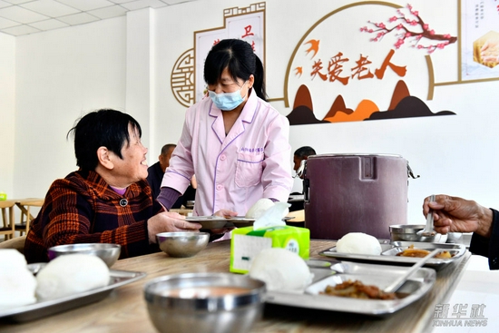 ↑在东营市垦利区杨庙社区养老服务中心，工作人员为老人盛午餐（10月18日摄）。