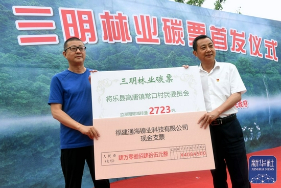 福建省三明市将乐县高唐镇常口联村党委书记张林顺（右）展示该村流转签约的林业碳票（5月18日摄）。新华社记者 彭张青 摄