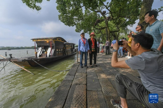  两名老党员在浙江嘉兴南湖湖心岛停泊的南湖红船旁拍照留影（7月1日摄）。新华社记者 徐昱 摄