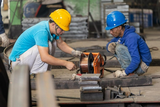  2019年11月7日，在老挝琅勃拉邦，中国技术人员（左）在钢筋加工厂教老挝工人检修设备。