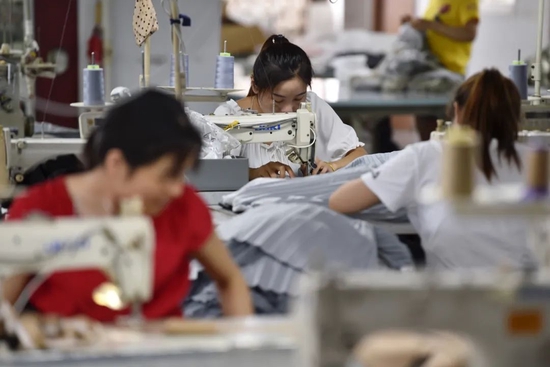 2021年7月15日，在江苏省南京市江宁区麒麟街道的一家服装厂，工人在裁缝车间制作服装。新华社发（方东旭 摄）