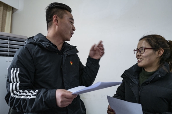  铁忠福（左）在昂仁县与同事交流工作（2021年12月21日）。新华社记者 孙瑞博 摄