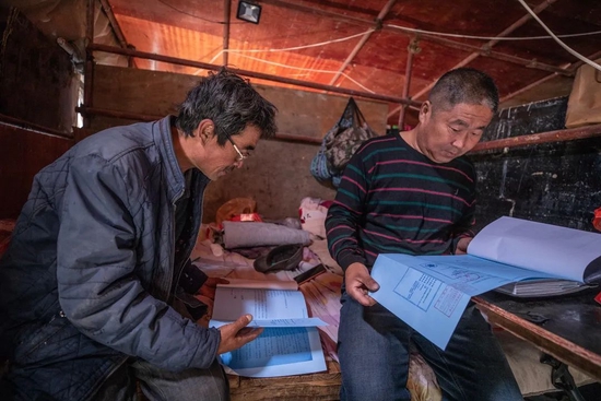 2020年9月17日，昌平区流村镇的明长城，两位工人在修缮现场附近的帐篷里查看施工图。