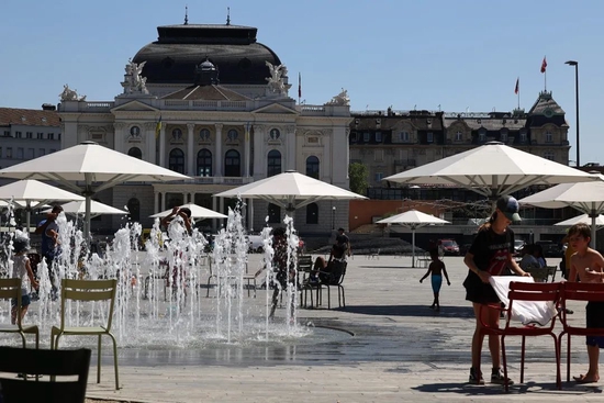 当地时间2022年7月19日，瑞士苏黎世，热浪笼罩着所有欧洲城市，这里是位于Bellevue广场和歌剧院之间的 "Sechseläuten广场"，儿童和成人在寻找阴凉处乘凉或是在喷泉处解暑。图/IC photo