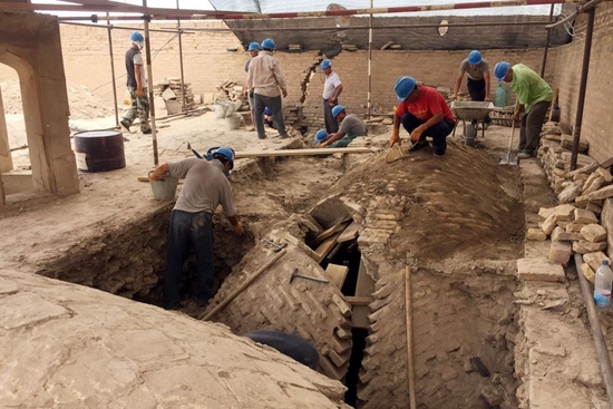 在乌兹别克斯坦希瓦古城阿米尔•图拉经学院，中乌文物修复人员在经学院东南角穹顶上方进行加固施工（2018年6月21日摄）。