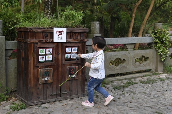  ↑在浙江省衢州江山市石门镇清漾村，小朋友将垃圾放入分类垃圾箱内（2018年4月20日摄）。