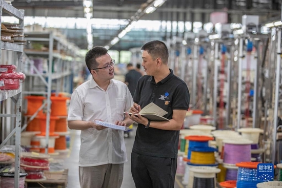 在重庆长秦汽车配件有限公司，重庆市璧山区高新区管委会的工作人员（右）在后工序车间内实地走访，了解企业遇到的困难（2022年7月19日摄）。新华社记者 黄伟 摄