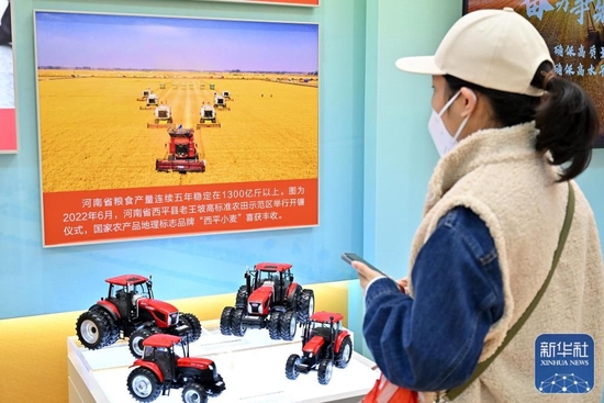  10月8日，一名观众在河南展区观看河南省西平县老王坡高标准农田示范区开镰仪式的图片。新华社记者 李鑫 摄