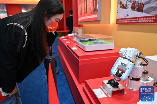  10月8日，一名观众在中央综合展区内观看六关节机器人测试鼠标寿命。六关节机器人是全球首款3kg负载高精度掌上六轴工业机器人，解决了关节机器人低速抖动的关键难点。新华社记者 李鑫摄