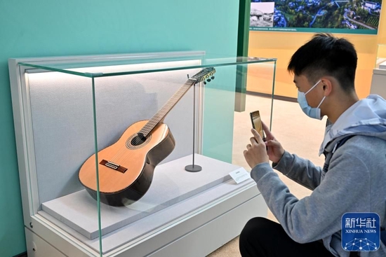 10月8日，一名观众在贵州展区拍摄正安吉他。贵州省正安县目前已成为全球最大吉他生产基地，已带动近15000人在家门口就业、6000余人稳定脱贫。新华社记者 李鑫 摄