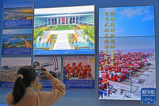  10月8日，一名观众在上海展区拍摄进博会主会场的宣传图。新华社记者 李鑫 摄