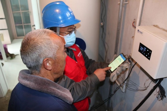 2022年11月，张北县油篓沟供电所工作人员到谢丽成家检查电供暖运行情况。（受访单位供图）