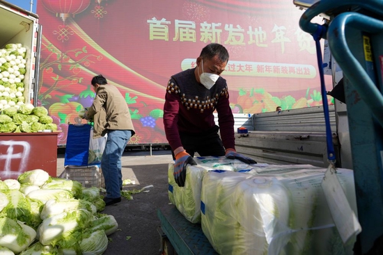  1月18日，在北京新发地农产品批发市场，工作人员将蔬菜装车准备转运。新华社记者 鞠焕宗 摄