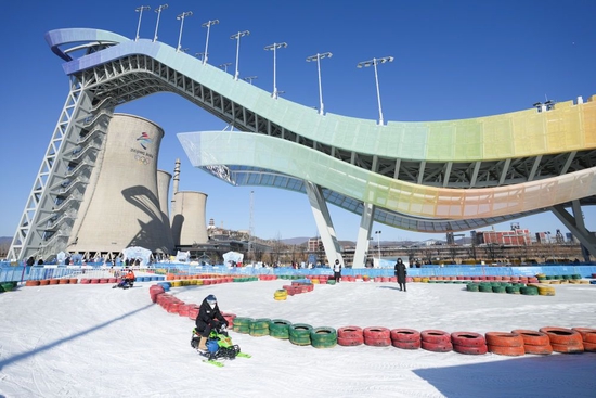 2023年1月15日，游客在首钢滑雪大跳台下体验雪地越野。2023年元旦开启的“首钢园冰雪汇”，让北京首钢滑雪大跳台成为大众冰雪乐园。新华社记者 鞠焕宗 摄