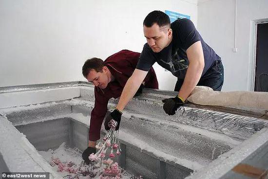 支属将鲜花放入尤里·皮丘金的棺材中,随后他的遗体被运去蓄积的地方。图片来源:east2west news