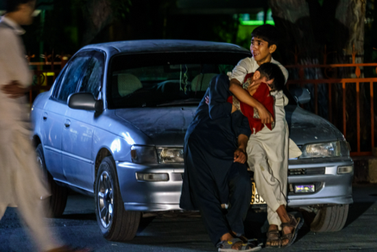 ▲爆炸救援现场，两名阿富汗男孩在汽车旁哭泣。图源/IC Photo