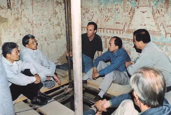 　　1999年7月，王旭东（右三）与中外专家在莫高窟第85窟壁画保护现场讨论（来源：敦煌研究院）