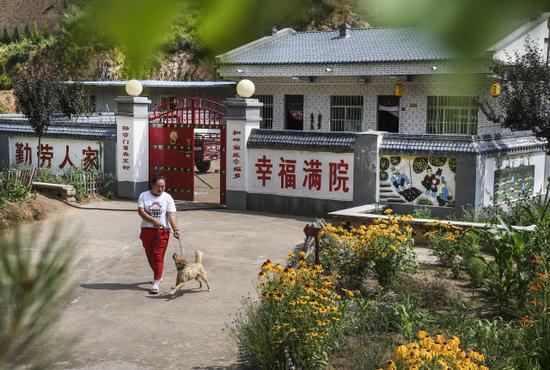 ↑在陕西省延安市宝塔区甘谷驿镇罗家湾村，村民田小霞在自家庭院前休闲（2018年6月26日摄）。新华社记者 陶明 摄